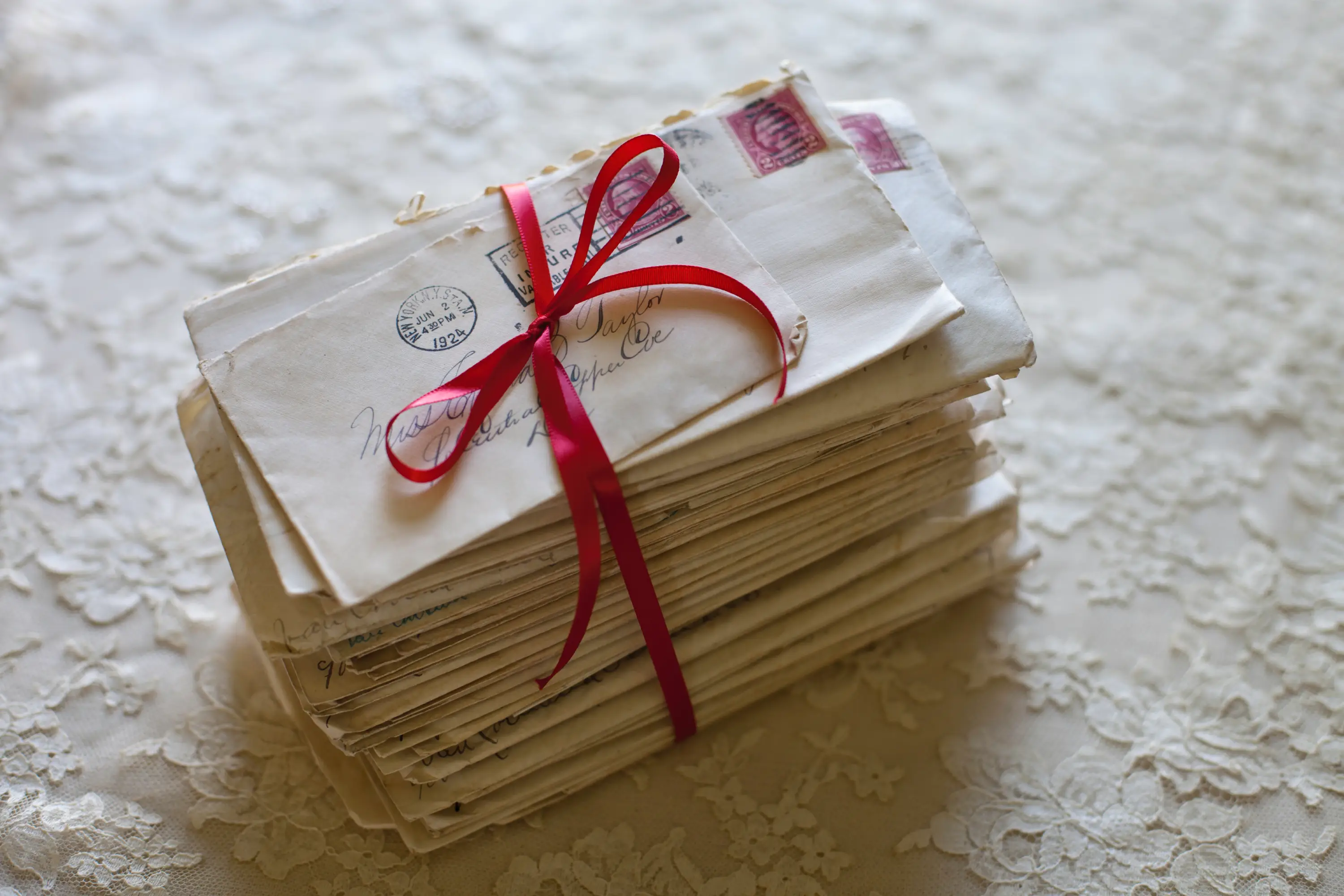 Stack of letters tied with red ribbon.