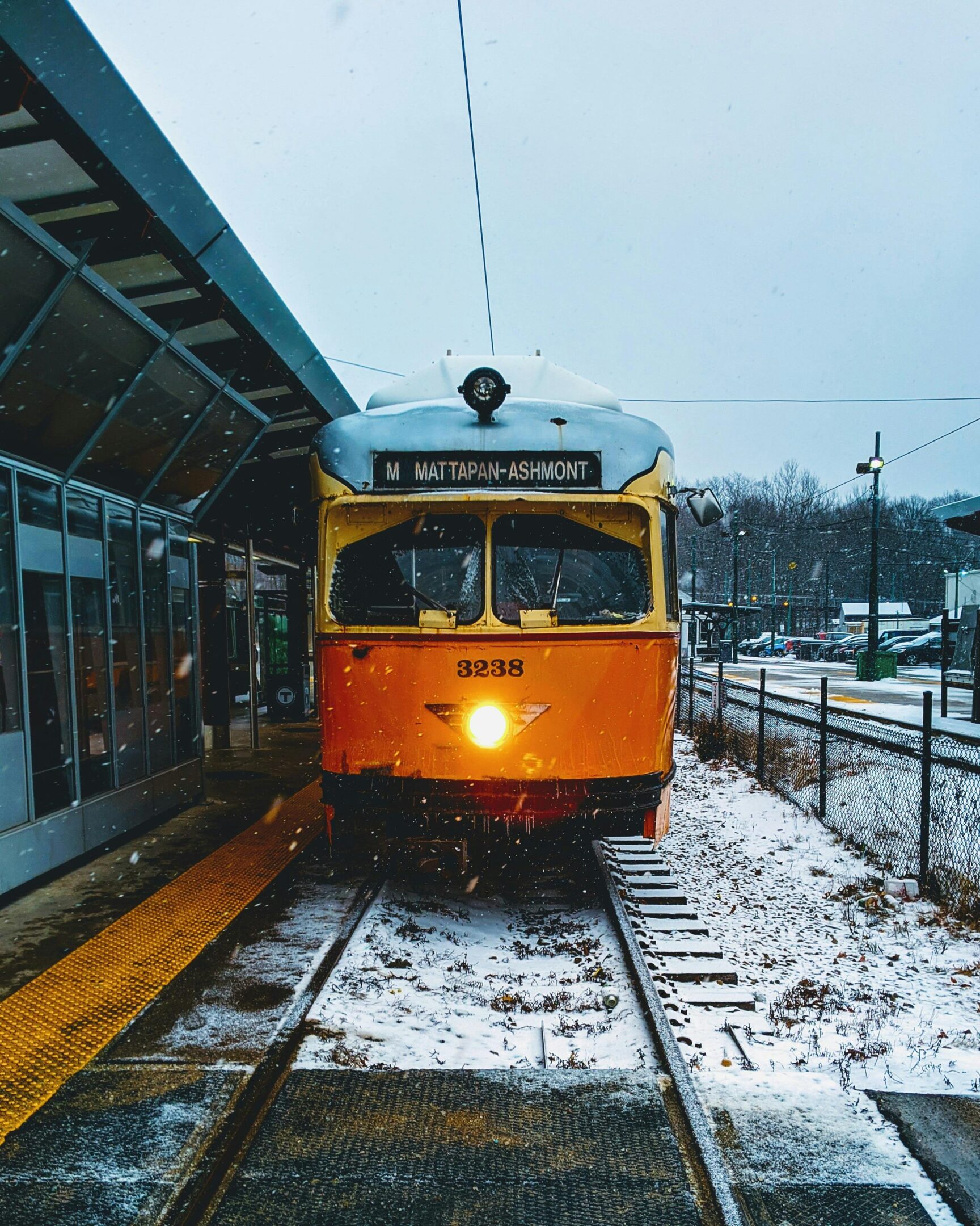 A yellow train at a snowy station platform in winter.