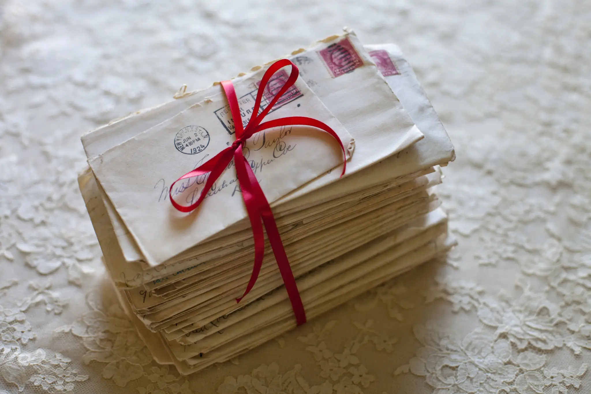 A stack of vintage letters tied with a red ribbon.