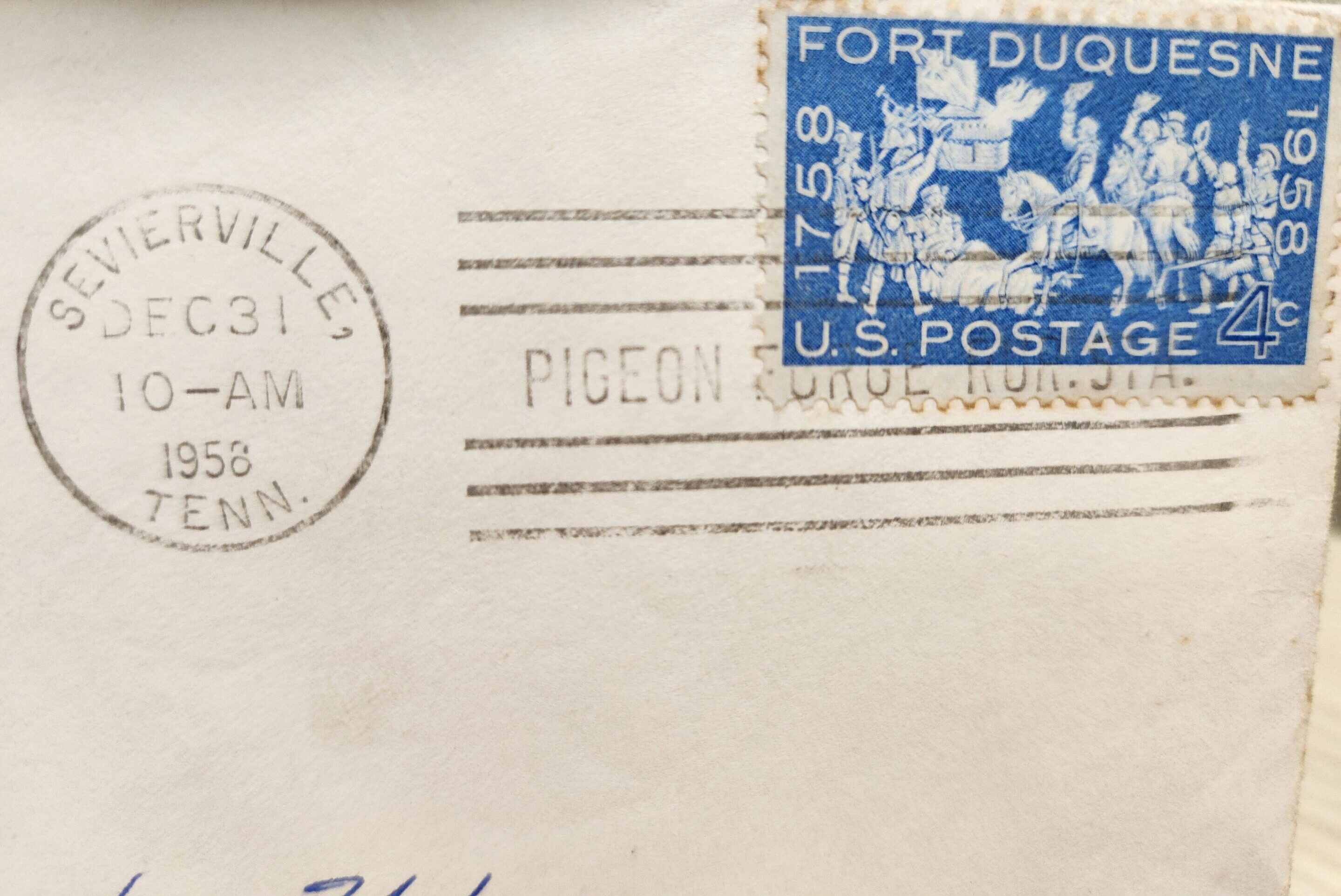 Close-up of an envelope corner with a blue postage stamp and postal markings.