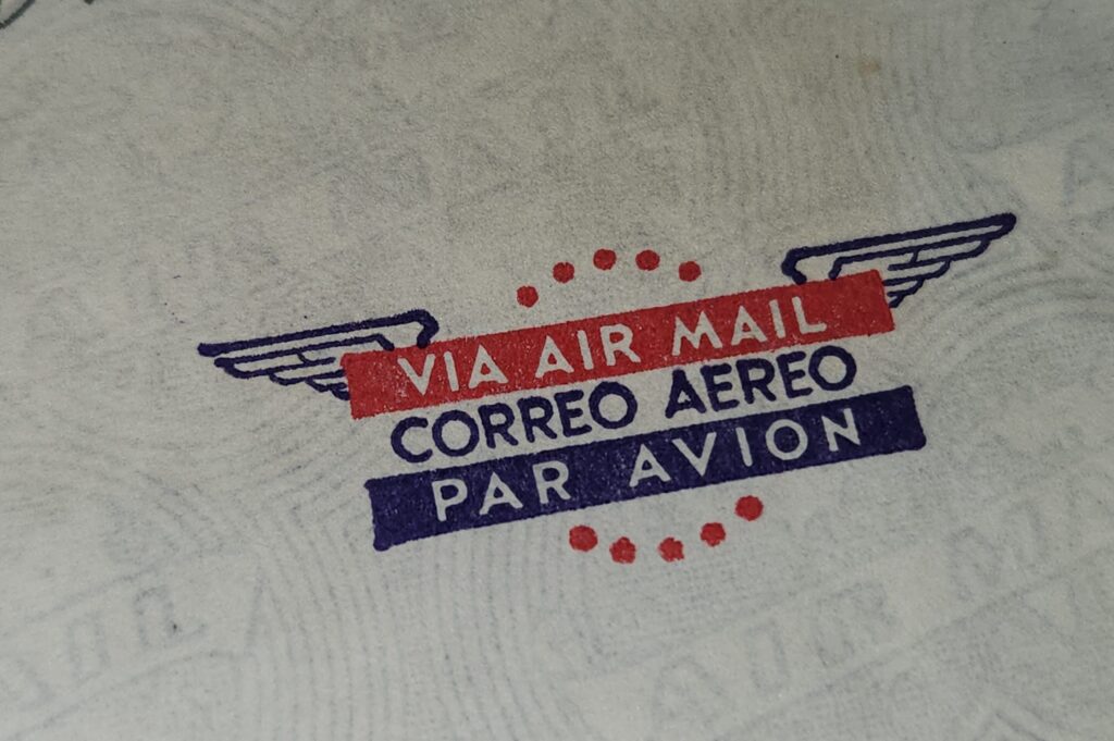 Vintage airmail stamp with multilingual text on paper.