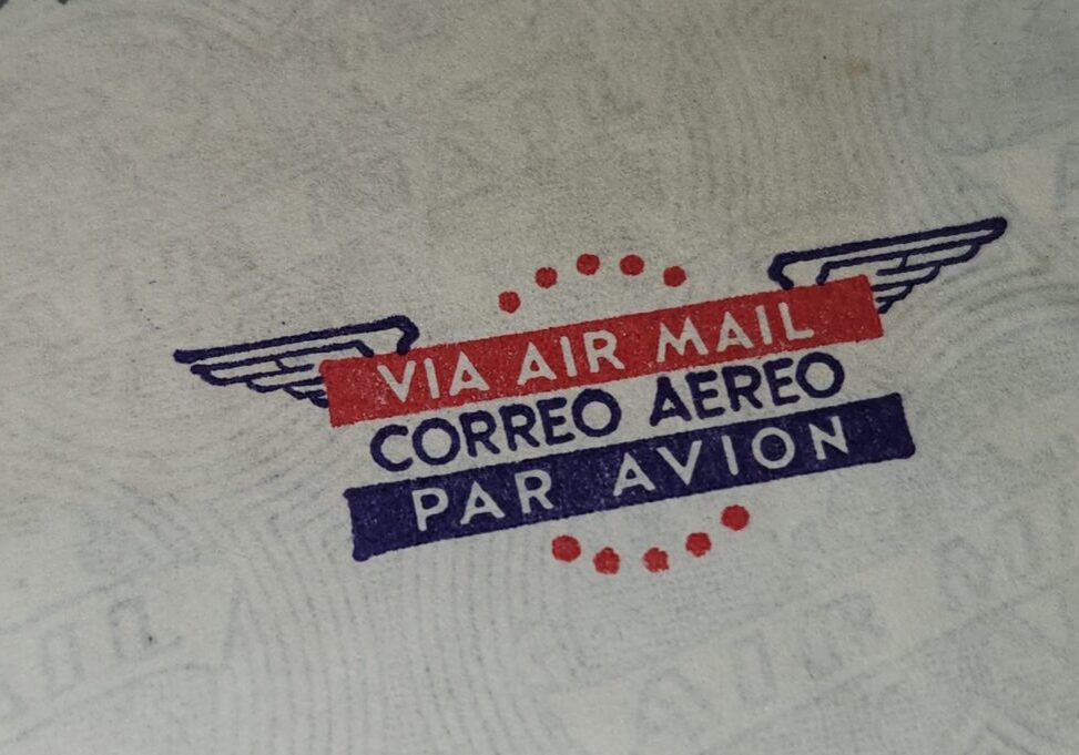 Vintage airmail stamp with multilingual text on paper.