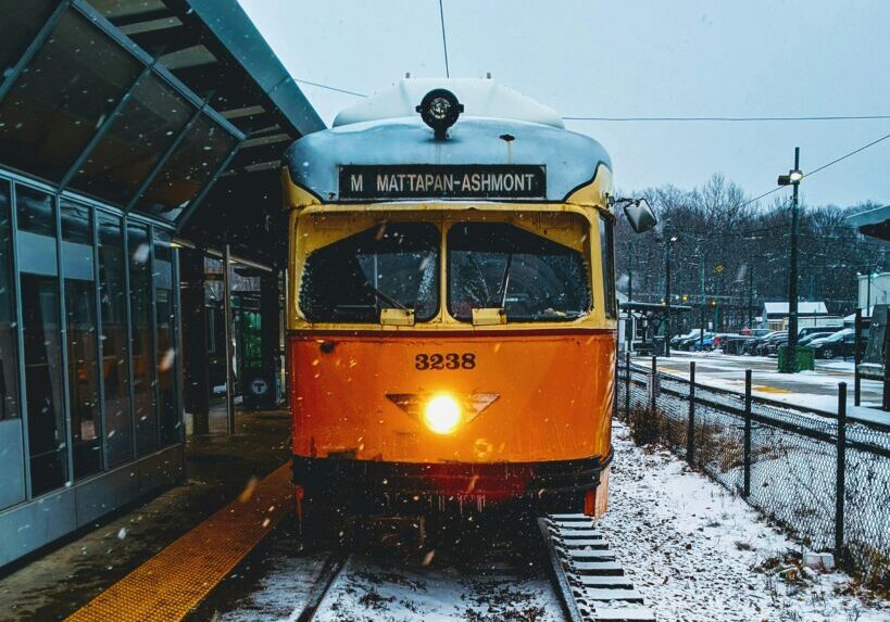 A yellow train at a snowy station platform in winter.