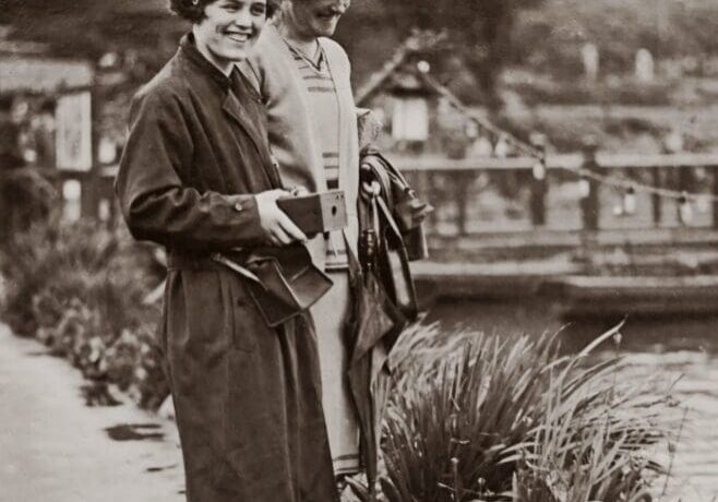 Two women smiling by a serene waterway.